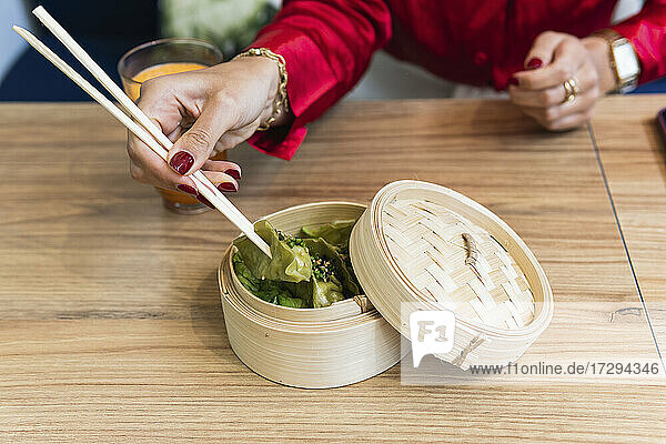Woman eating with chopsticks at restaurant