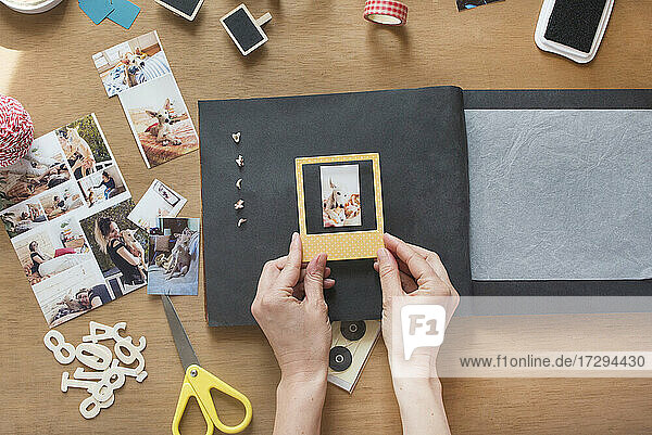 Woman sticking frame over dog photo in scrapbook