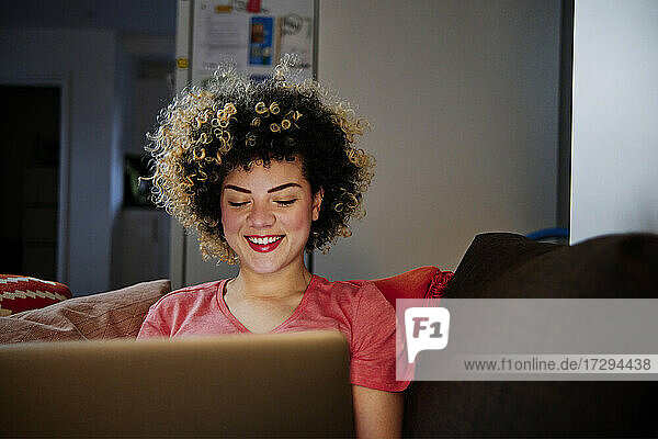 Lächelnde schöne Frau mit Laptop im Wohnzimmer zu Hause