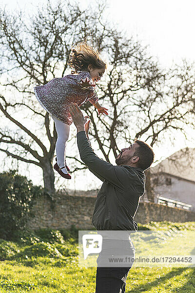 Father catching daughter while enjoying weekend during springtime