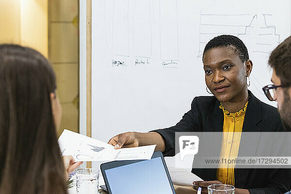 Geschäftsfrau  die ein Dokument mit einer weiblichen Fachkraft während einer Besprechung im Büro teilt