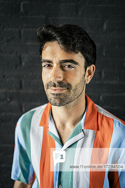 Smiling man with black hair in multi colored striped shirt