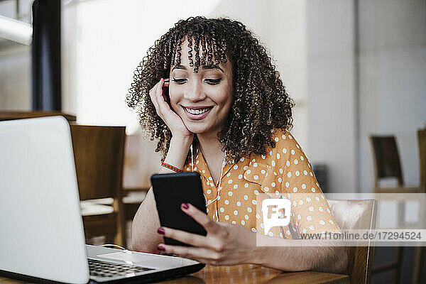 Smiling businesswoman using mobile phone in coffee shop