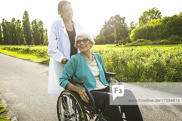 Hausmeisterin mit älterer Frau im Rollstuhl im Park