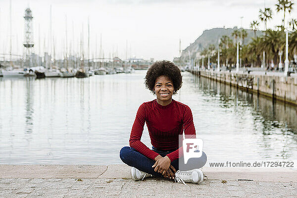 Junge Afro-Frau auf der Promenade in der Stadt sitzend