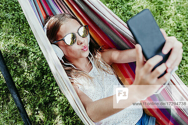 Girl wearing sunglasses puckering while taking selfie in hammock