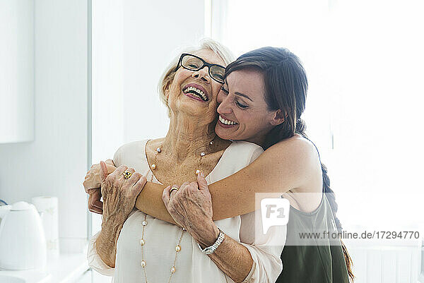 Fröhliche Frau umarmt Großmutter in der Küche zu Hause