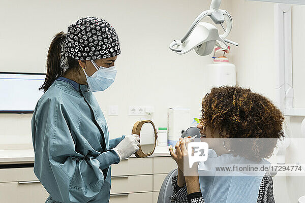 Lächelnde Patientin  die den Zahnarzt anschaut  während sie in der Klinik eine Zahnspange trägt
