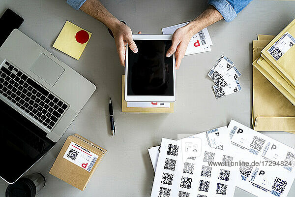 Geschäftsmann hält digitales Tablet über Box am Schreibtisch