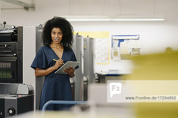 Afro female entrepreneur looking away while working on digital tablet at industry