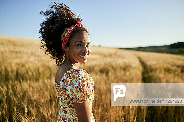 Glückliche schöne Frau mit lockigem Haar in einem Weizenfeld