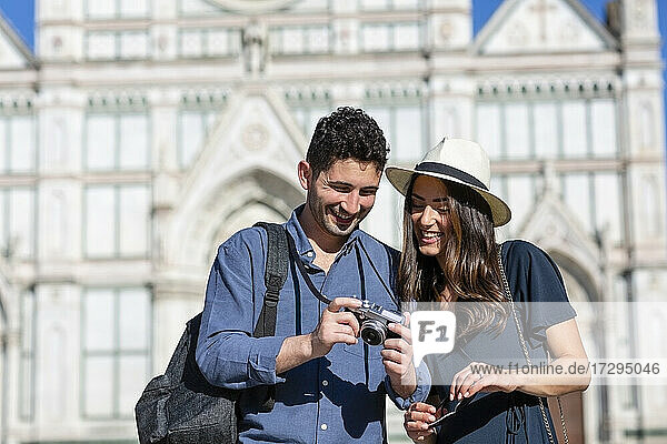Lächelnde Touristen beim Überprüfen der Kamera mit der Basilika Santa Croce im Hintergrund in Florenz  Italien