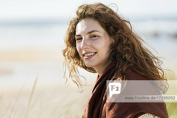 Beautiful redhead woman smiling at beach during sunny day