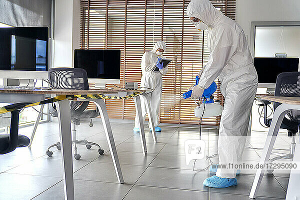 Sanitärarbeiter beim Versprühen von Desinfektionsmitteln im Büro