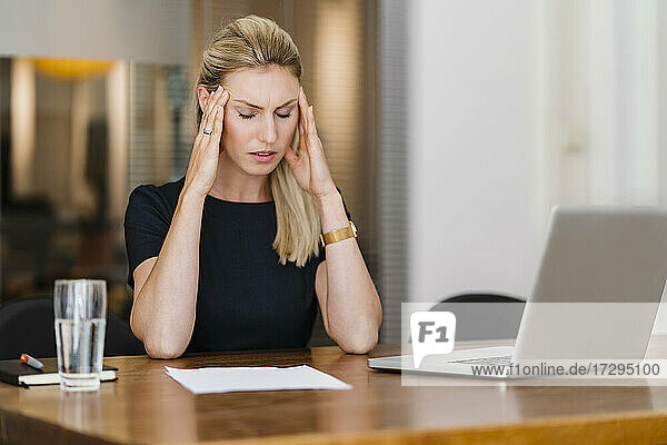 Müde weibliche Fachkraft sitzt am Schreibtisch im Büro