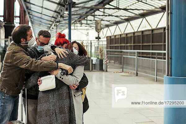 Freunde umarmen sich am Bahnhof während der COVID-19