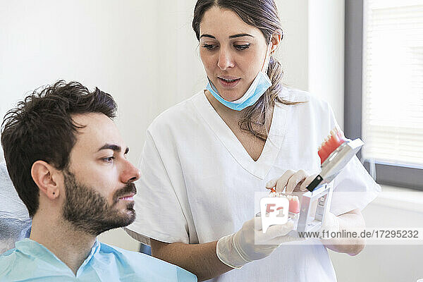 Eine Zahnärztin erklärt einem Patienten in einer medizinischen Klinik ein Zahnmodell