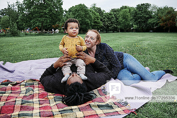 Glückliche Familie entspannt sich mit ihrem Sohn auf einer Picknickdecke im Park