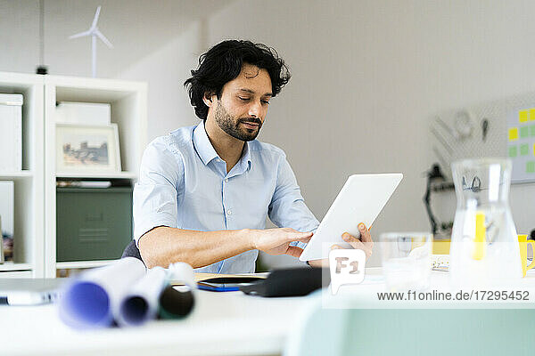 Young male entrepreneur using digital tablet while sitting at office