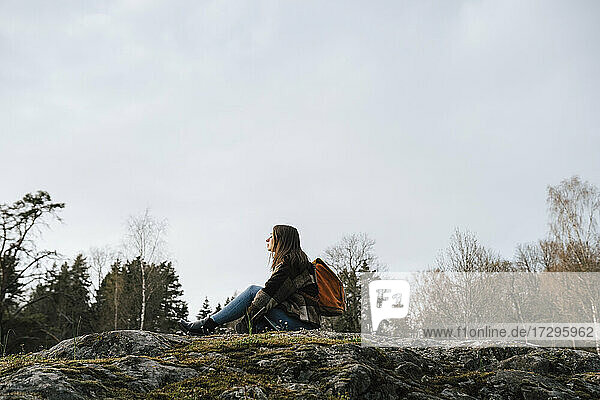 Weibliche Entdeckerin verbringt Freizeit  während sie auf einem Berg im Wald sitzt