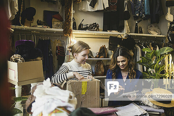 Lächelnder Besitzer  der ein digitales Tablet benutzt  steht neben einer Kollegin in einer Boutique