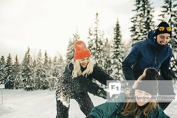 Glückliche männliche und weibliche Freunde spielen im Skigebiet im Winter