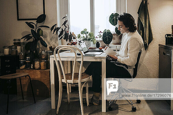 Geschäftsmann sitzt mit Laptop schreiben  während der Arbeit von zu Hause