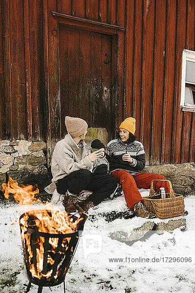 Homosexuelles Paar mit Tochter gegen Hütte im Winter
