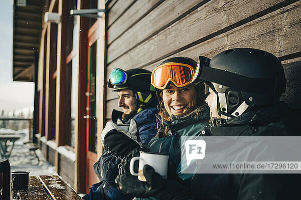Glückliche männliche und weibliche Freunde verbringen Freizeit beim Kaffee trinken im Skigebiet
