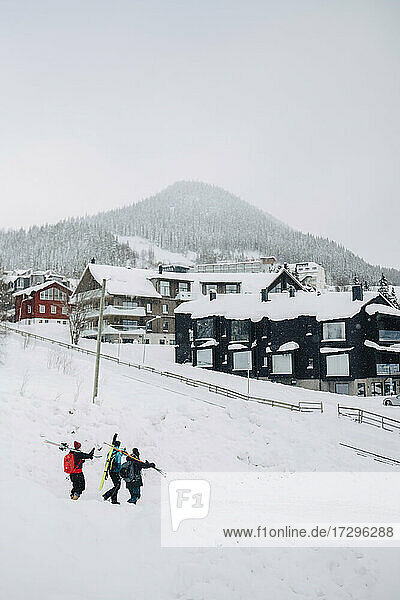 Männliche und weibliche Freunde zu Fuß auf Schnee im Winter im Skigebiet