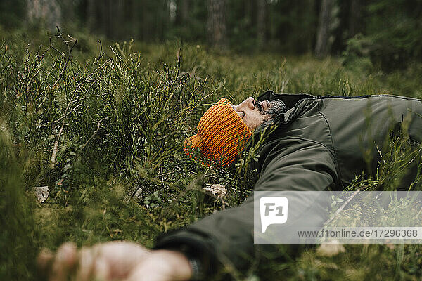 Männlicher Forscher ruhend auf Gras im Wald