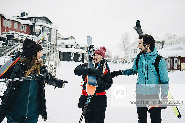 Cheerful male and female friends carrying skis during winter