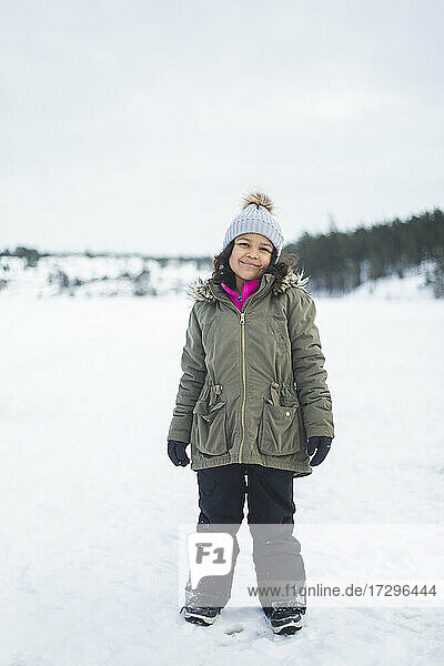 Full length of smiling girl standing on snow