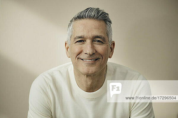 Smiling mature man against beige wall