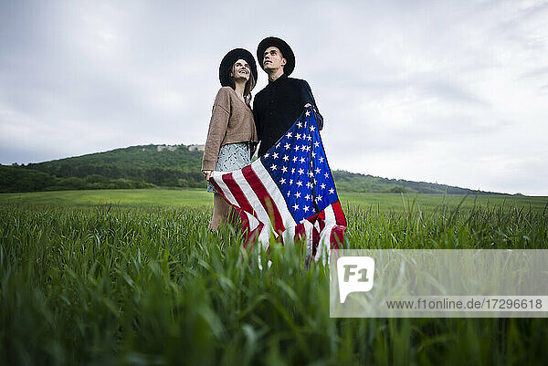 Junges Paar hält amerikanische Flagge in einem Weizenfeld