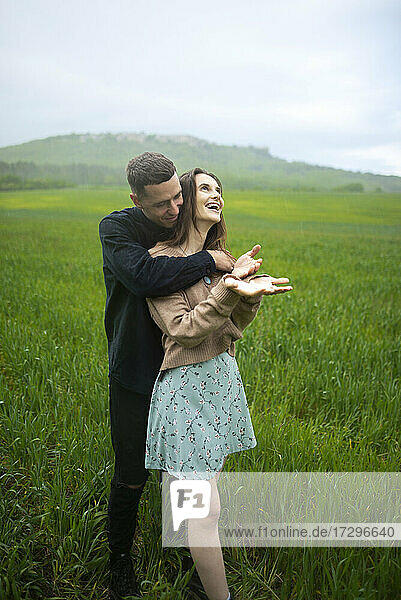 Junges Paar umarmt sich im Weizenfeld bei Regen