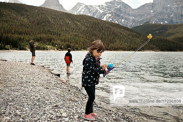 Young girl fishing with her dad and brother at a mountain lake