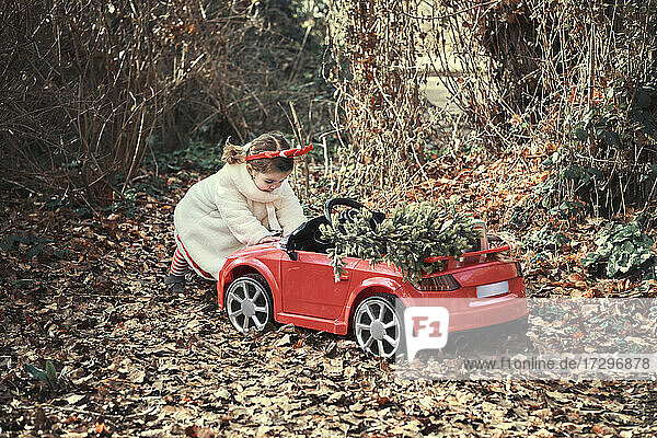 Ein Mädchen in einem Weihnachtskostüm in ihrem roten Auto