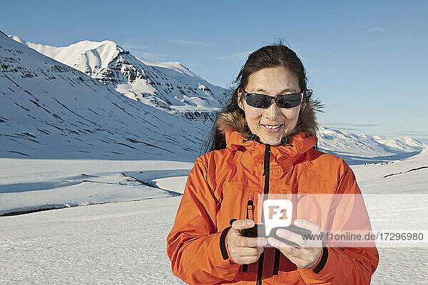 Frau  die in den Bergen von Nordisland eine SMS auf ihrem Smartphone schreibt