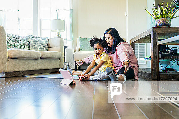 Girl practicing yoga with grandmother during online exercise class at home