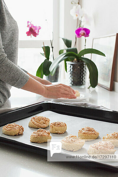 Blurred woman put cookie to a plate from baking sheet against th
