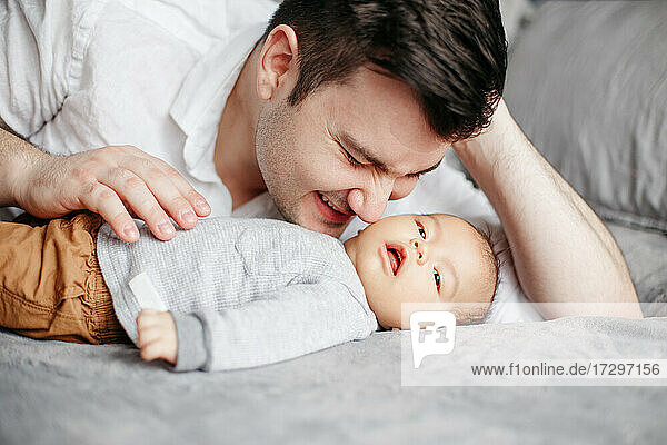 Closeup of happy smiling dad father kissing newborn baby boy son.