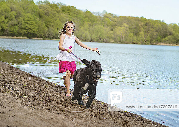 Little Girl Running on a Beach with Black Dog