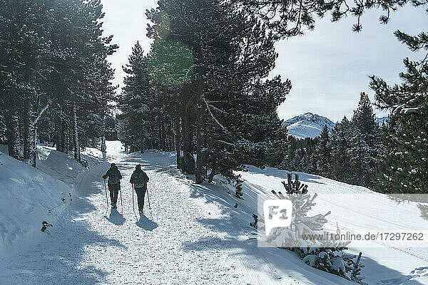 2 Personen wandern im Schnee in Richtung eines Berggipfels