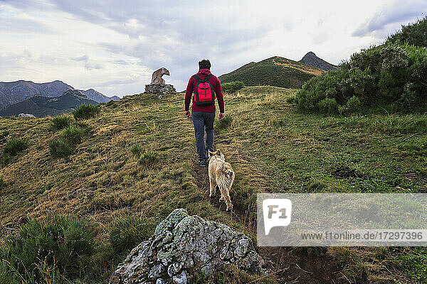 Mann beim Wandern in den Bergen mit einem Hund in den Picos de Europa