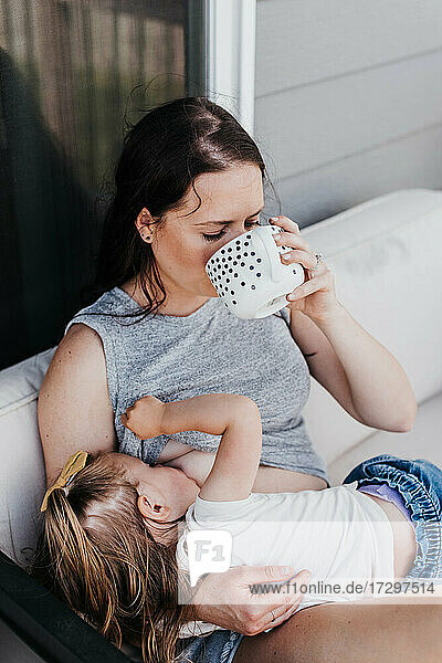 Mutter stillt Kleinkind an einem Sommertag auf ihrer Veranda