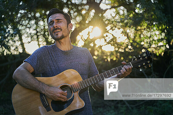 junger Mann spielt Gitarre bei Sonnenuntergang
