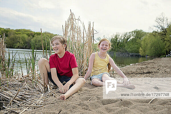 Young Boy and Girl Playing in the Sand by a Lake