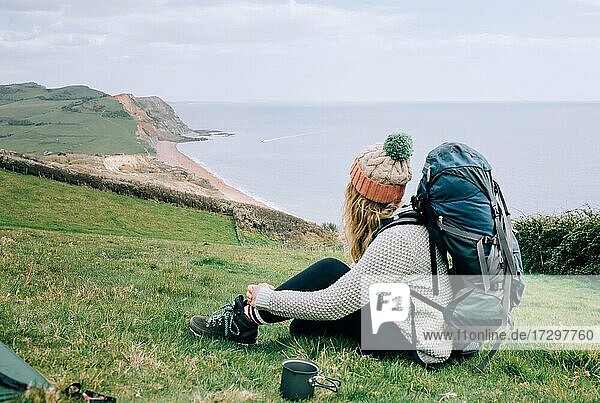 Frau beim Wandern an der Juraküste in England mit einer Tasse Tee beim Camping