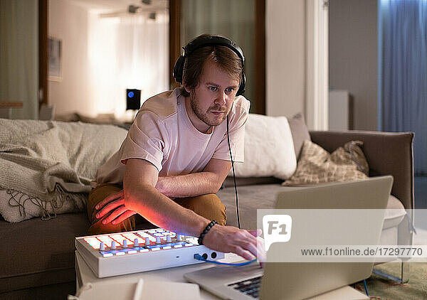 Männlicher DJ mit Laptop auf dem Sofa
